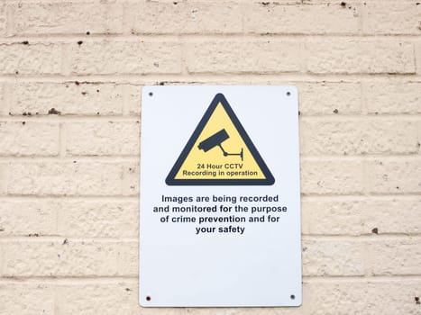 a white placard sign on wall surveillance cctv warning  England  UK