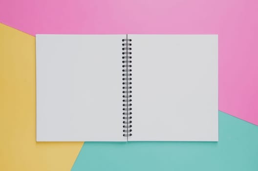 Office workplace minimal concept. Blank notebook on yellow, pink and green turquoise background. Top view with copy space, flat lay. Pastel color filter.