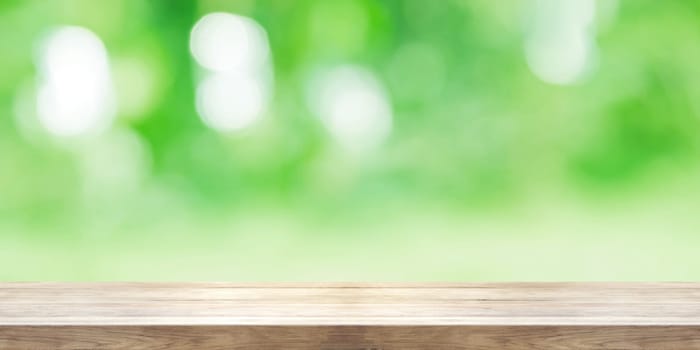 Empty wooden table top with blurred green natural abstract background. Panoramic banner. Can be used product display.