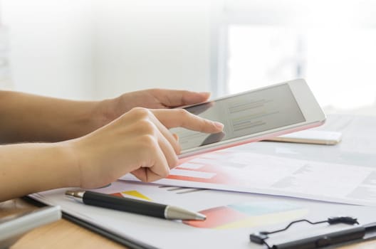 Business, office concept. Woman's hands using tablet with financial document.