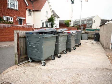 a row of black waste bins outside full  England  UK