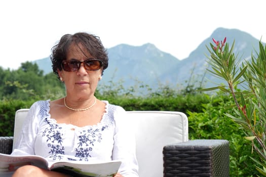 portrait of  smiling middle age woman with sunglasses  sitting in garden at home