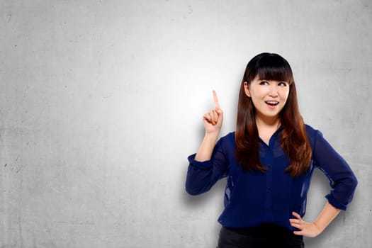 Pretty asian woman pointing empty space with confidence over grunge background
