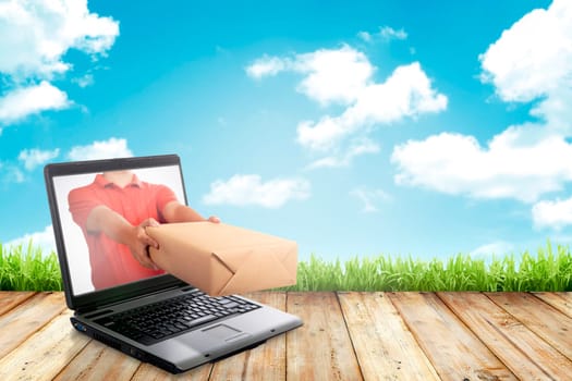 Hand giving a box out of laptop screen. Online shopping concept