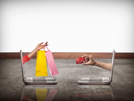 Hand out from computer carry shopping bag, the other show credit card. Online shopping conceptual