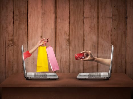 Hand out from computer carry shopping bag, the other show credit card. Online shopping conceptual
