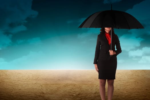 Business person holding umbrella standing on the desert
