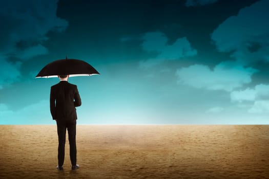 Business person holding umbrella standing on the desert