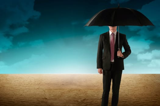 Business person holding umbrella standing on the desert