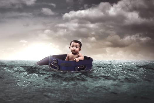 Cute little baby float inside suitcase in the middle of the sea