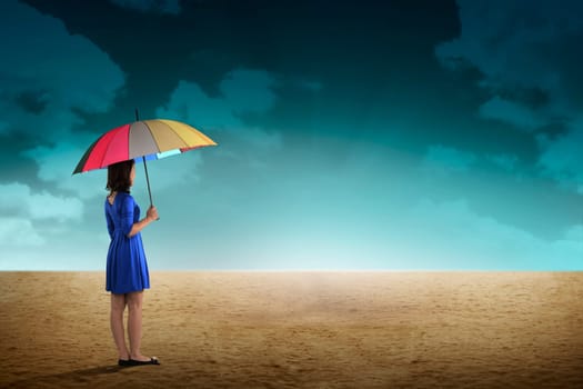 Business person holding umbrella standing on the desert