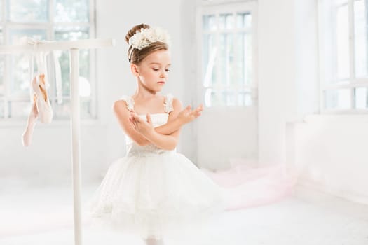 Little ballerina girl in a tutu. Adorable child dancing classical ballet in a white studio. Children dance. Kids performing. Young gifted dancer in a class. Preschool kid taking art lessons.