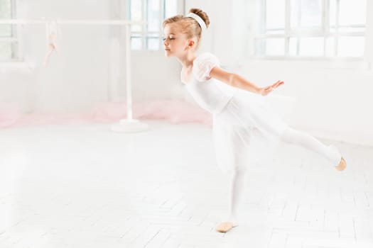 Little ballerina girl in a tutu. Adorable child dancing classical ballet in a white studio. Children dance. Kids performing. Young gifted dancer in a class. Preschool kid taking art lessons.