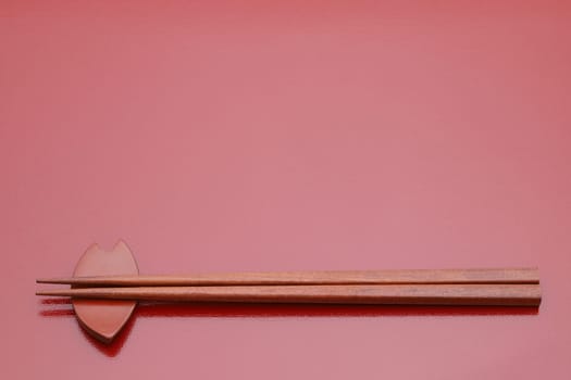 Chopsticks and chopsticks rest on red table background