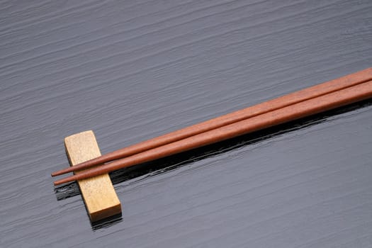 Chopsticks and chopsticks rest on black table background