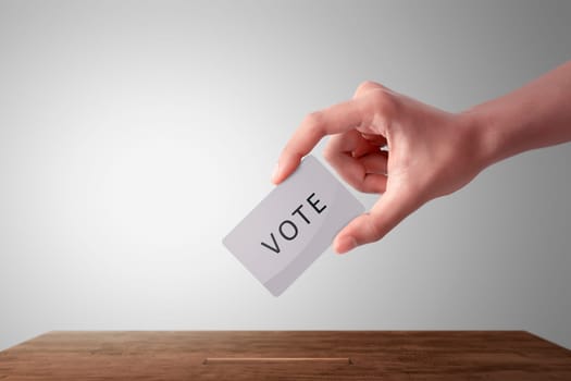 Person hand giving his vote in a ballot box against white background