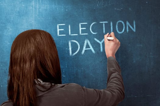 Beauty woman writing a 'ELECTION DAY' on blue chalkboard. Election day background or concept