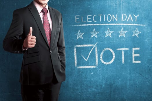 Man with business suit standing beside 'Election Day' writed on chalkboard.