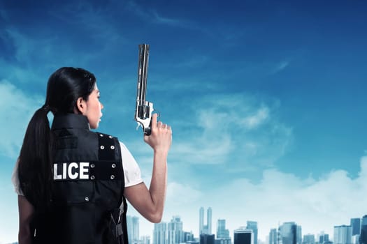 Beautiful police woman holding gun ready to fire