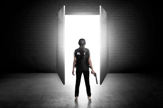 Police woman holding gun looking the door. Police concept
