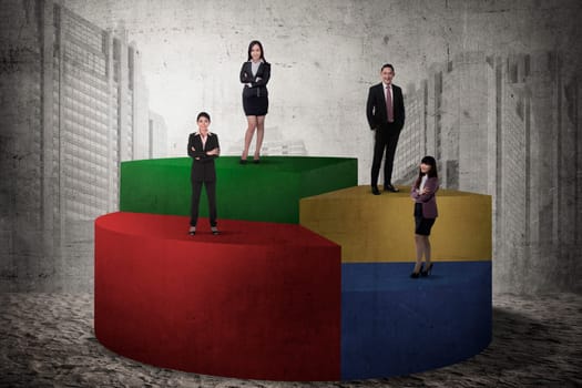 Asian business team standing on pie chart. Business people concept