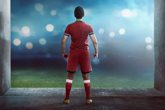 Back view of asian football player standing on hallway to the field
