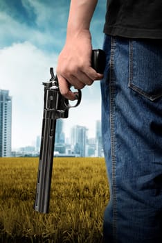 Man hand holding gun on the green field