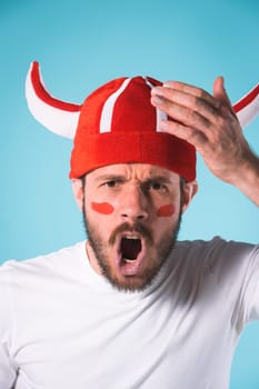 The football fan over blue. The young man looking at camera with different emotions on face
