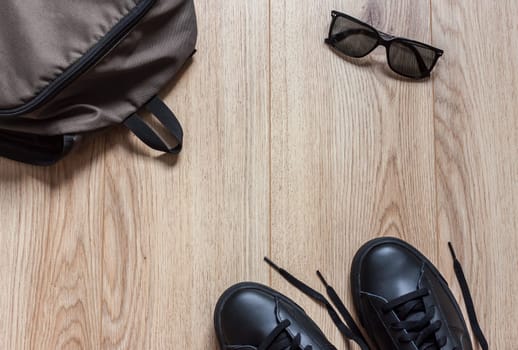 top view backpack glasses and sneakers on wooden background