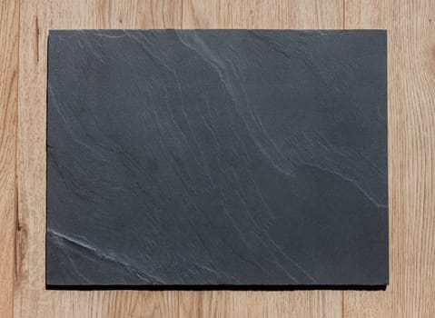 empty stone black plate on wooden table surface
