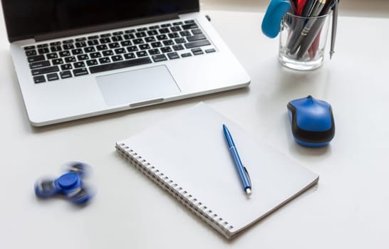 work desk with laptop mouse glasses and spinner