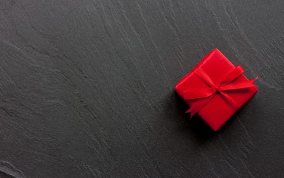red beautiful wraped gift box on black background