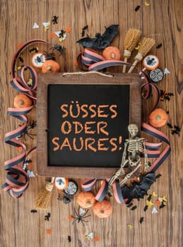 Colorful decoration and sweets for Halloween on background made of wood