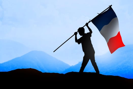 Silhouette of man holding france flag standing on the mountain