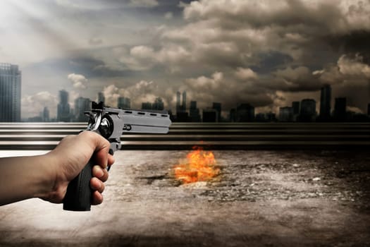 Man hand holding gun and aiming to the burn city