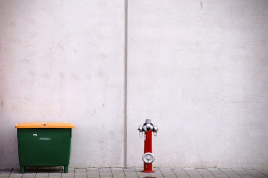 A grit container and a fire hydrant in front of the striking concrete façade of a stadium.