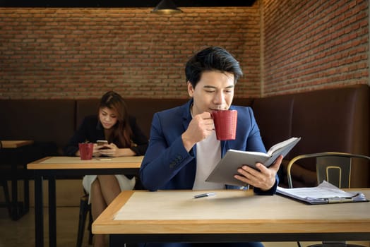young asian businessman working while drinking red cup coffee in the office