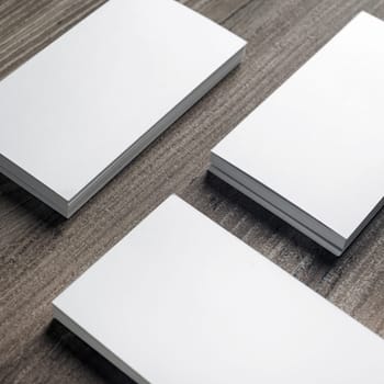 Stacks of blank business cards on wooden background.