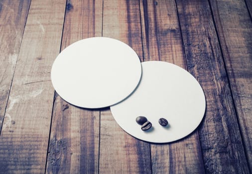 Photo of blank white beer coasters and coffee beans on wooden background.