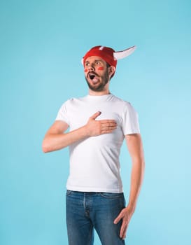 The football fan with megaphone over blue. The young man looking at camera with different emotions on face