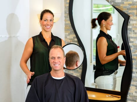 female hairdresser cutting hair of man in her shop