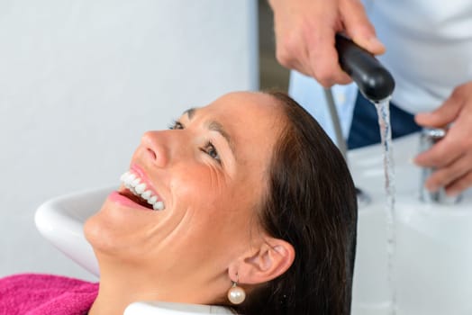 hairdresser washing hair of woman in his shop