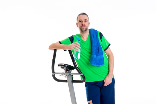 young man in green shirt with water bottle train with fitness machine