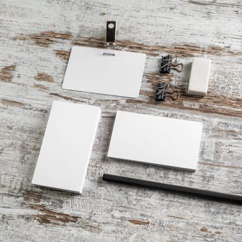 Photo of blank stationery on wood table background. ID template. Bank business cards, badge, pencil and eraser on vintage wood table background.