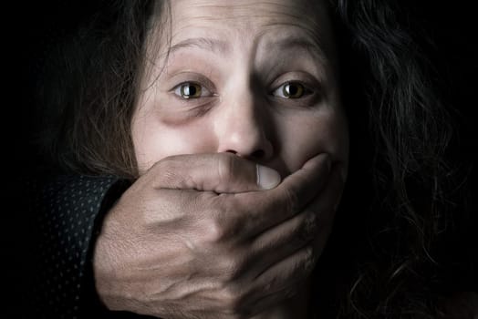 Scared woman with man's hand covering her mouth, victim of domestic violence
