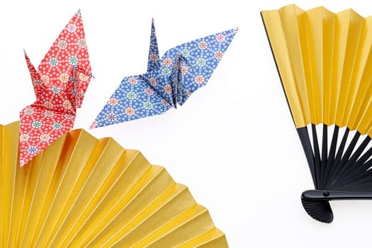 golden folding fan and origami bird isolated on white background
