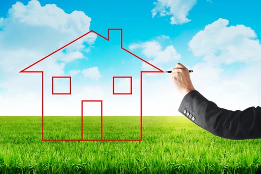 Business man drawing house on the meadow with blue sky background