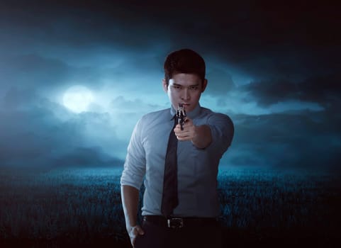 Asian man aiming gun on the meadow field