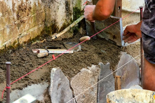 Workers laying and clinkering natural stone slabs.