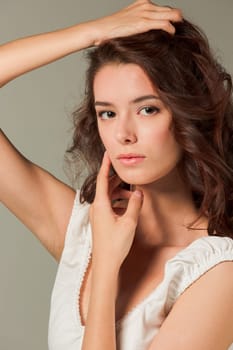 The face of young woman with long hair on gray studio background
